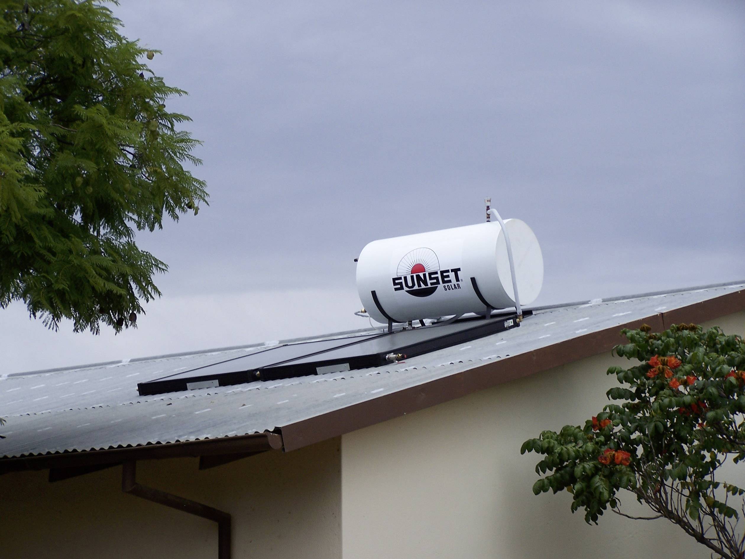 Eine Solarthermie-Anlage mit Kollektoren und Warmwasserspeicher ist auf einem Dach montiert.