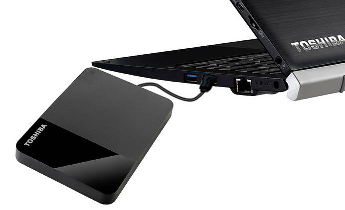 Schwarze, portable externe Festplatte von Toshiba per USB 3.0 am Laptop angeschlossen für schnellen Datentransfer.