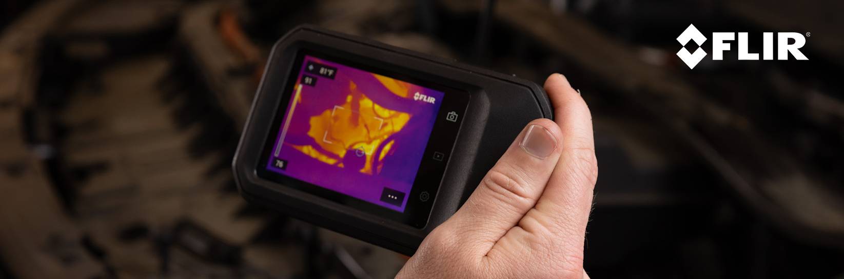 Hand hält FLIR Wärmebildkamera mit farbigem Display.