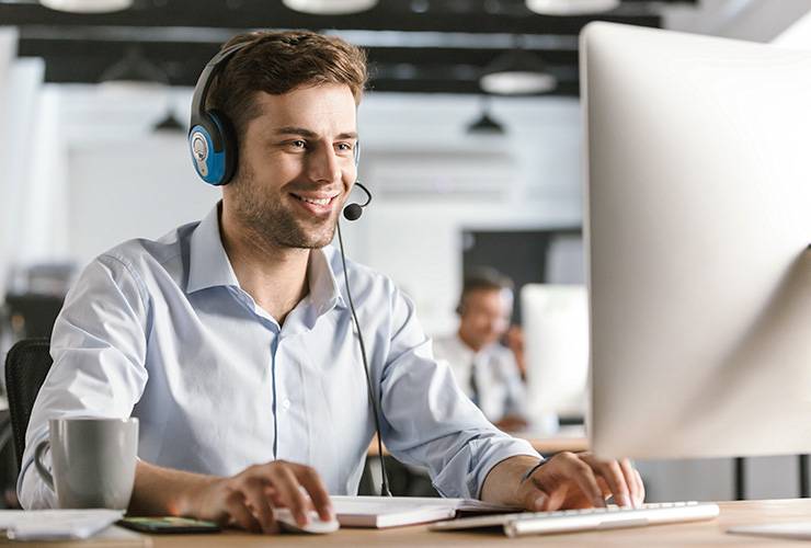 Personne devant un ordinateur portable utilisant une souris et portant un casque noir et bleu