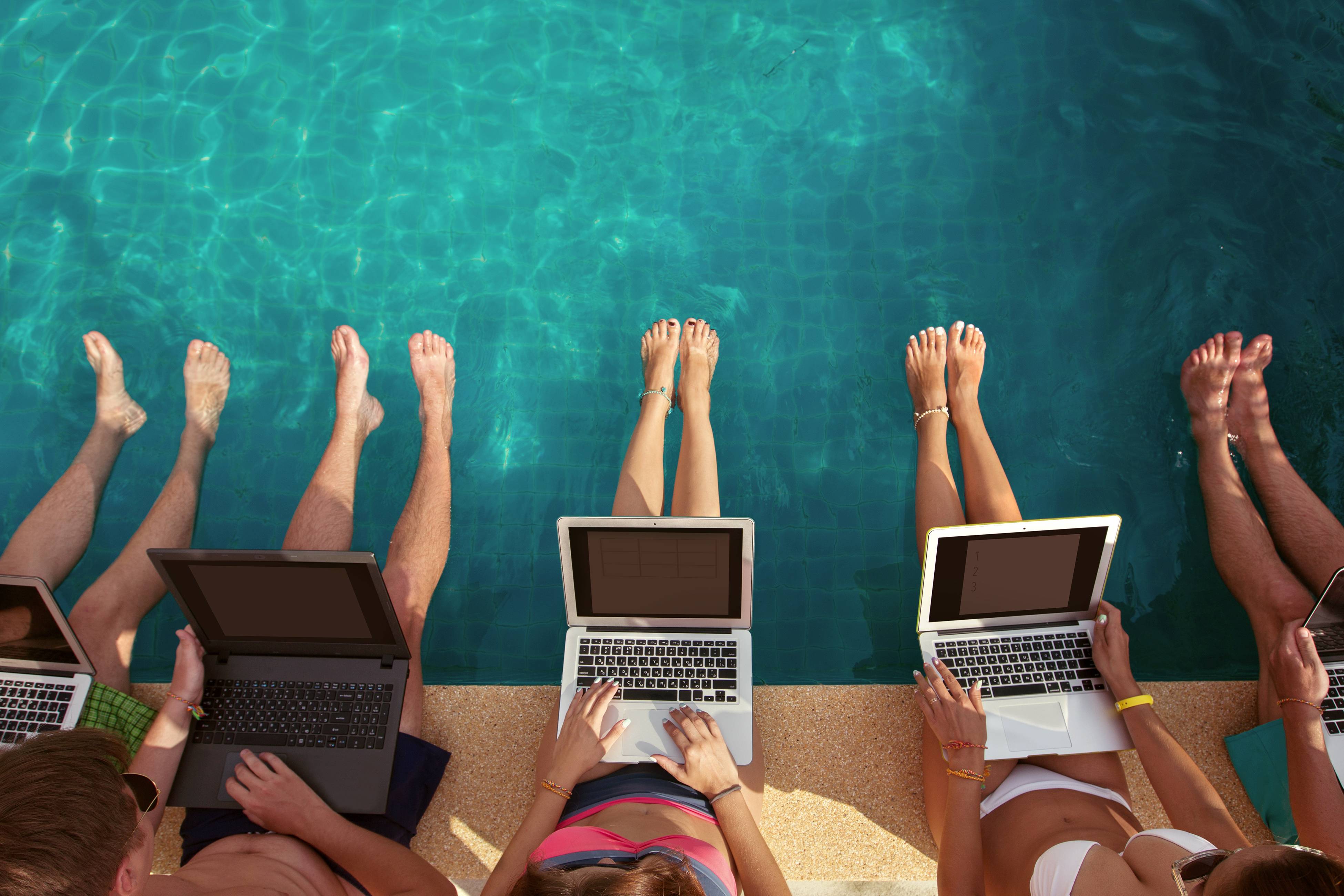 Auf diesem Bild sind 5 Menschen zu sehen, die an einem Pool mit einem Laptop arbeitet