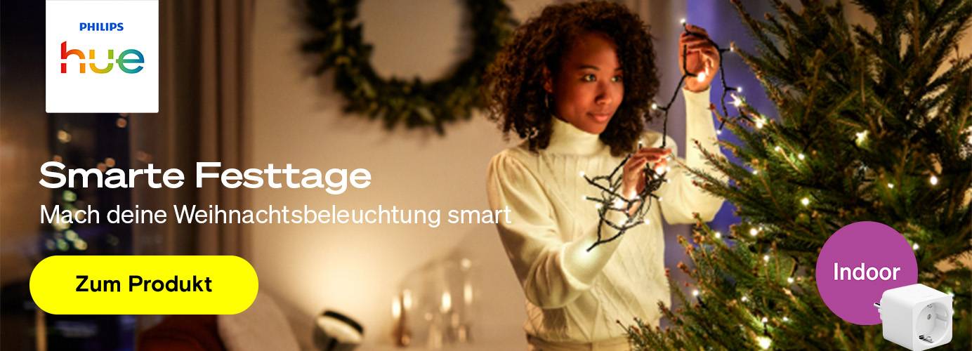 Eine Frau dekoriert einen Weihnachtsbaum mit smarten Philips Hue Lichterketten für smarte Festtage.