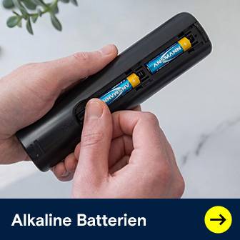 Zwei Hände legen Ansmann Alkaline Batterien in eine Fernbedienung ein, bereit für den Einsatz.