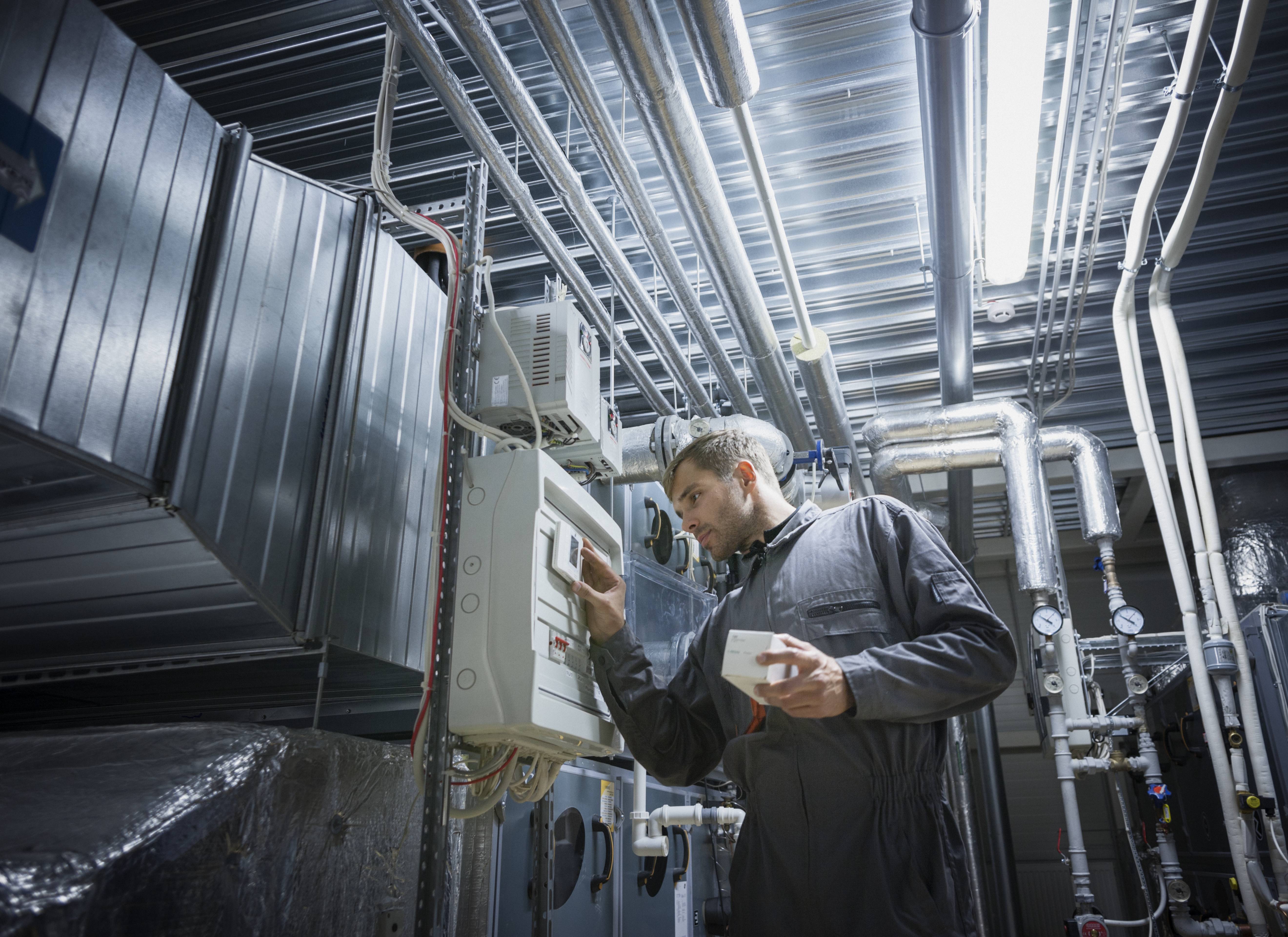 Techniker prüft Steuerung in industrieller Anlage, wo Temperaturfühler zur Temperaturregelung verwendet werden.
