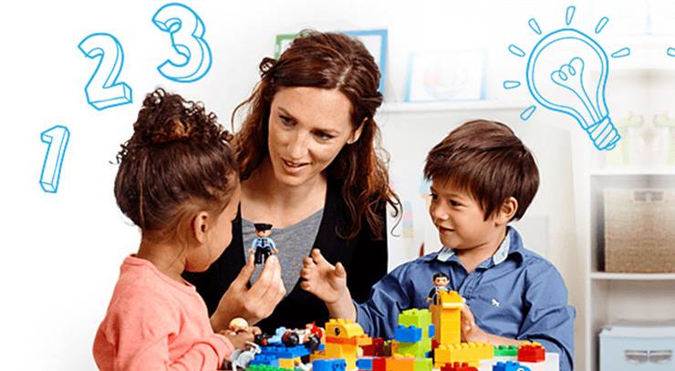 Erzieherin spielt mit zwei Kindern und bunten Lernbausteinen in einer Lernumgebung.