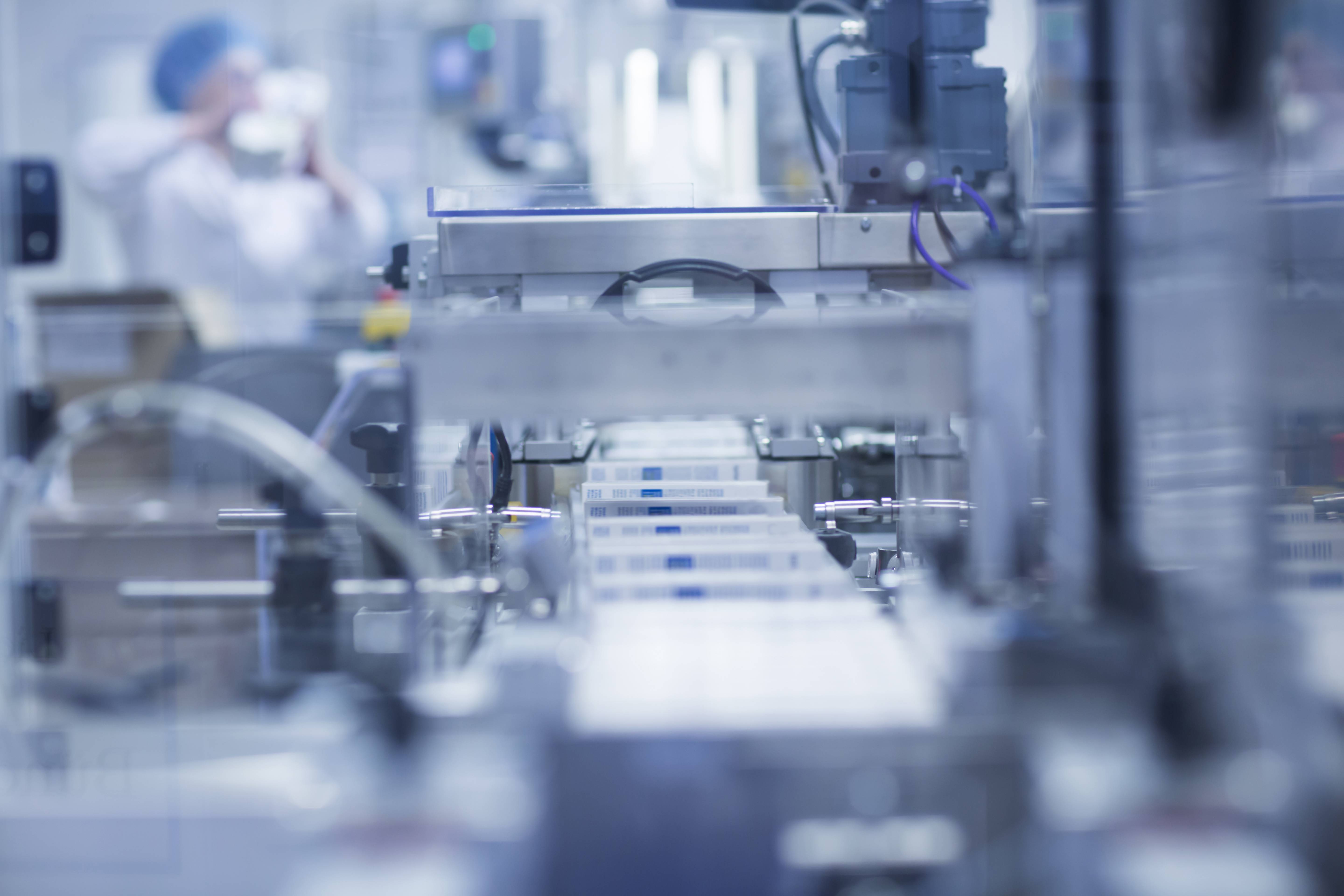 Produktionsstraße, auf der viele Verpackungen entlangfahren. Nur das Zentrum des Bildes ist scharf erkennbar.