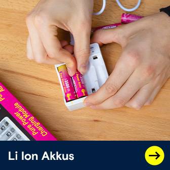Hände legen pinkfarbene Li-Ion Akkus in ein weißes Ladegerät auf einem Holztisch.