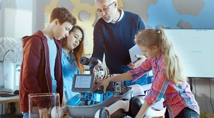 Lehrer und Schüler arbeiten gemeinsam an einem Roboterprojekt im Technikunterricht.