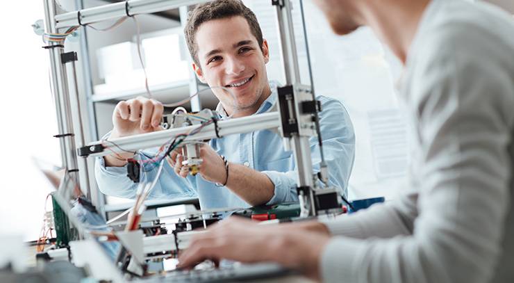 Studierende bauen und programmieren gemeinsam ein technisches Gerät im Labor.