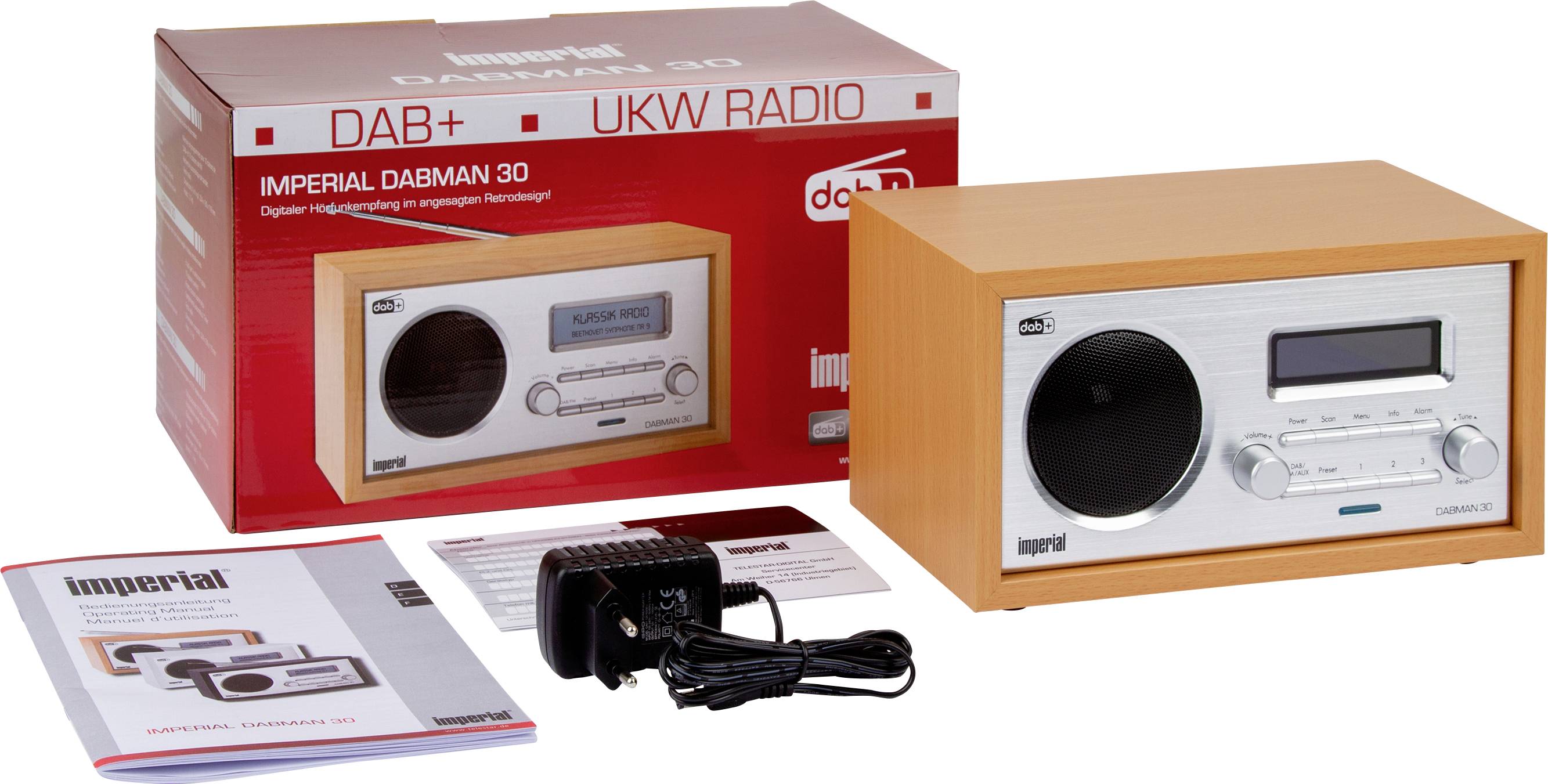 Retro designové rádio s regulátorem hlasitosti a displejem, vedle karton se stejným rádiem, prospekt a napájecí adaptér.
