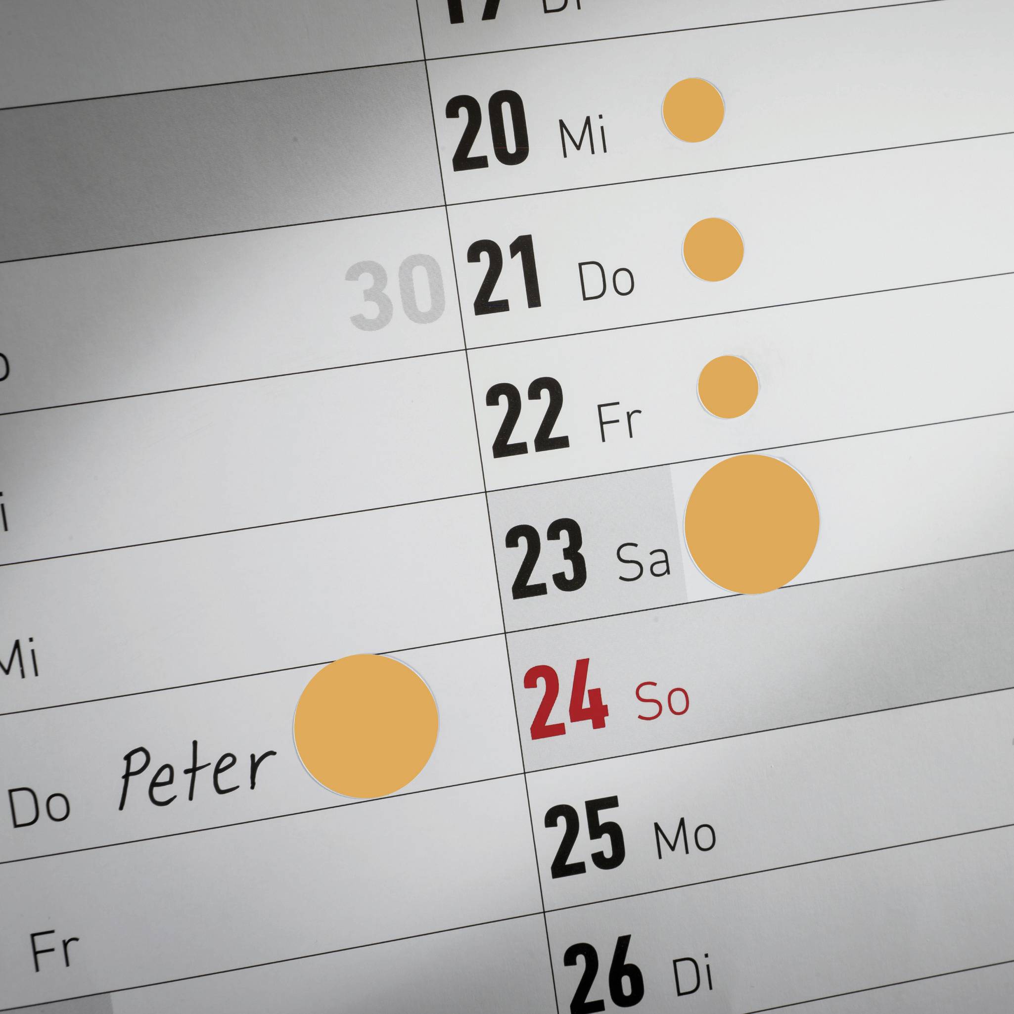 Kalendář ukazuje týden od 20. do 26., s oranžově vyznačenými kruhy 21., 22. a 23. a červeně vyznačeným kruhem u jména 'Peter' dne 24.