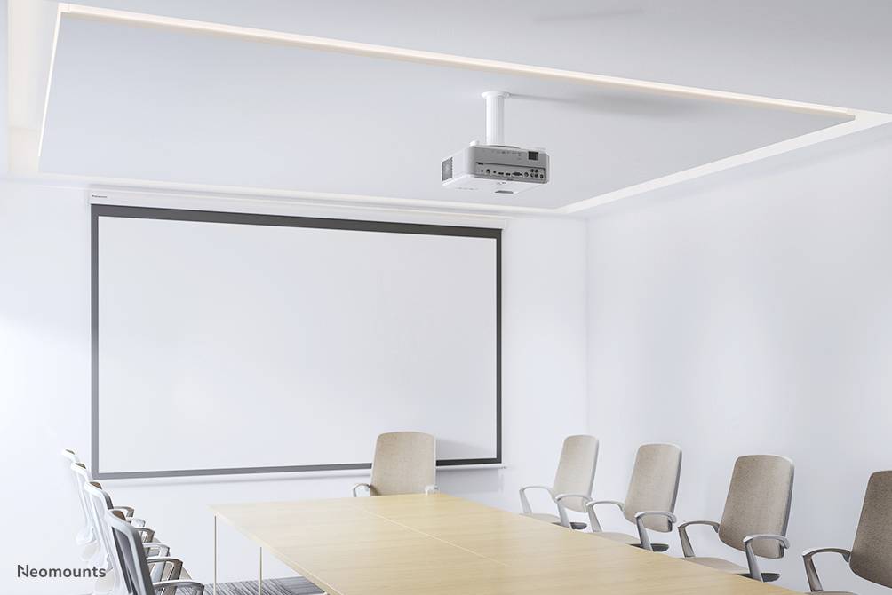 Konferenční místnost s velkým projektorem, dlouhým dřevěným stolem a několika židlemi. Světlé, minimalistické vybavení.