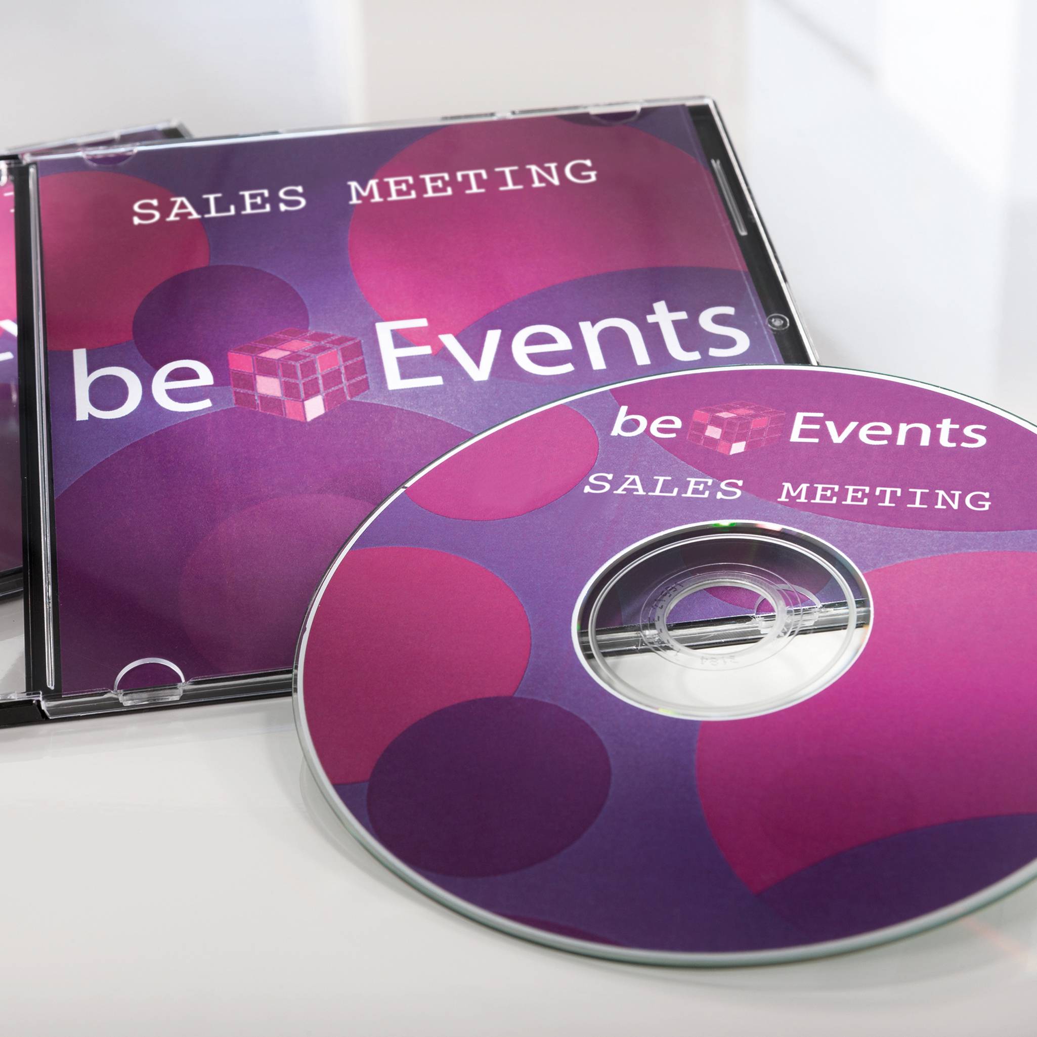Obal CD a disk s designem v lila-růžových odstínech; viditelný text 'Sales Meeting' a 'be Events'.