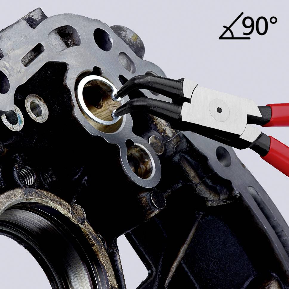 Dvě černé a červené kleště odstraňují kroužek z kovového strojního dílu v úhlu menším než 90 stupňů.
