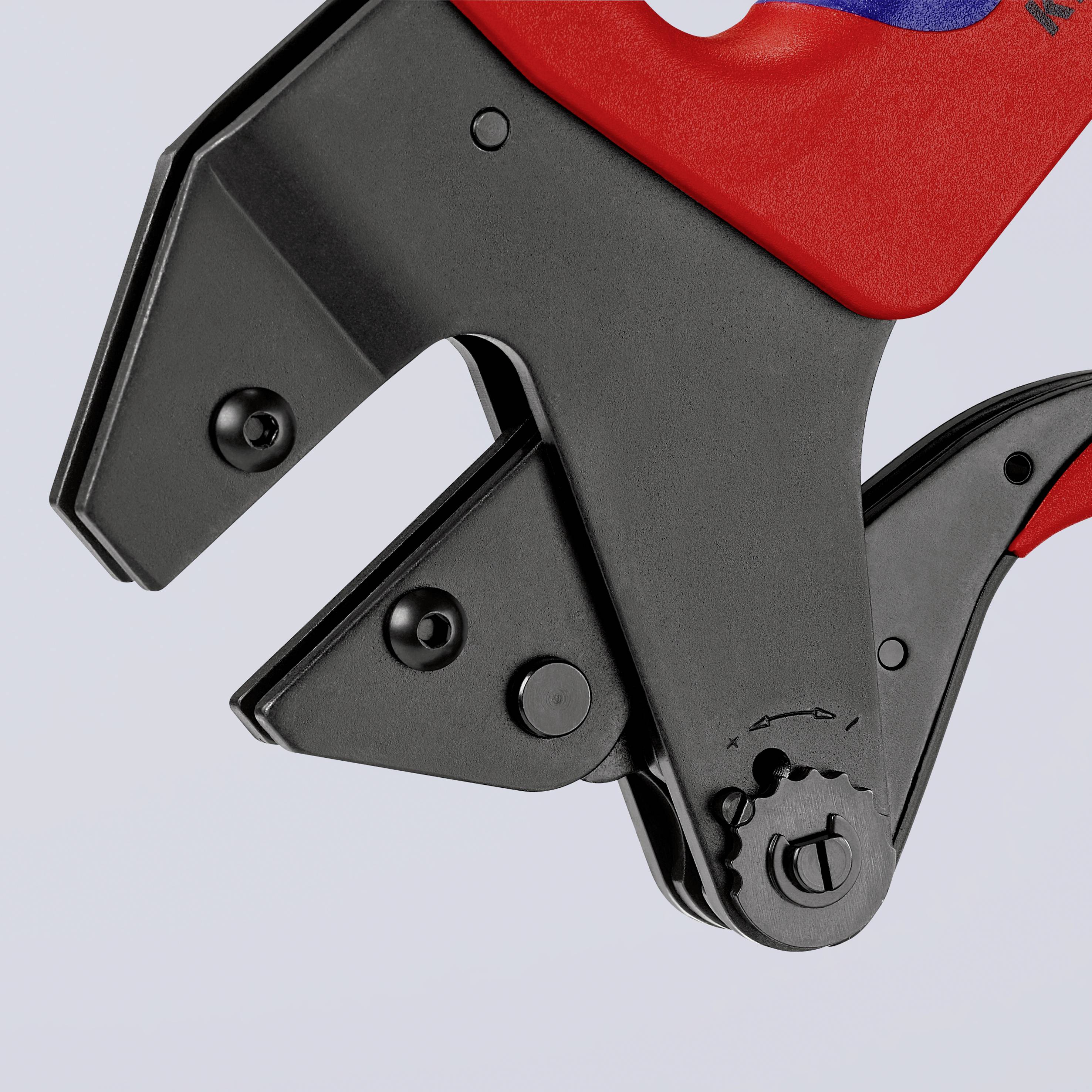 Detail mechanismu černého kovu s červeným plastovým držadlem, pravděpodobně nástroj pro lehký průmysl nebo domácí řemeslné práce.