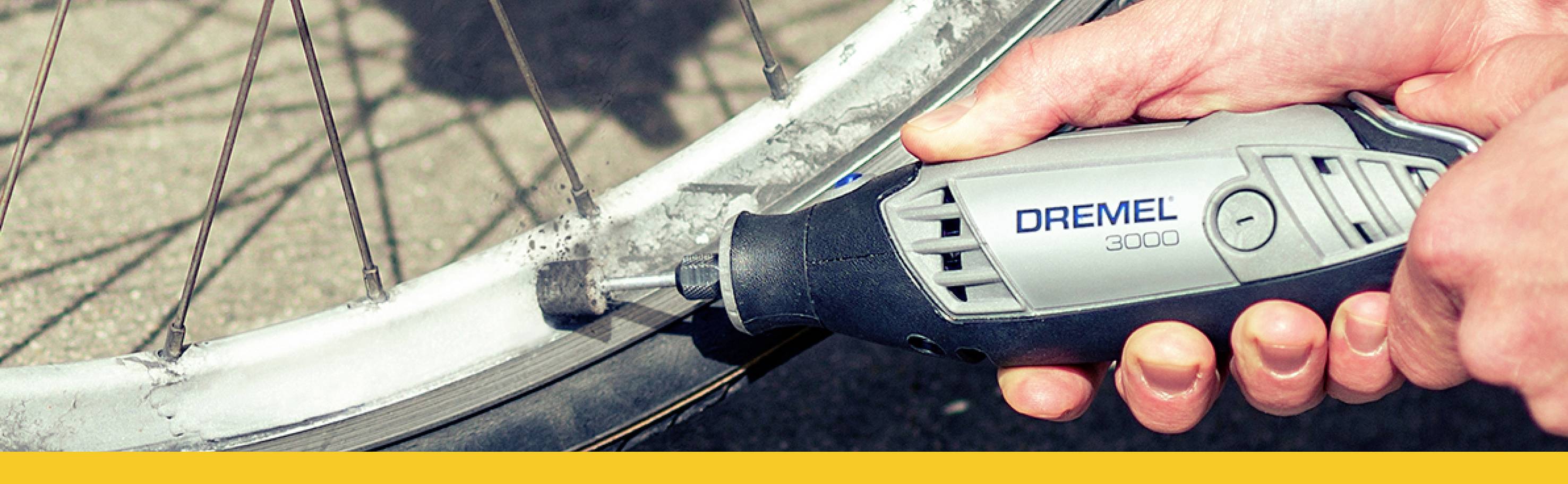 Jedna ruka drží nástroj Dremel a přebrušuje okraj cyklistické pneumatiky.
