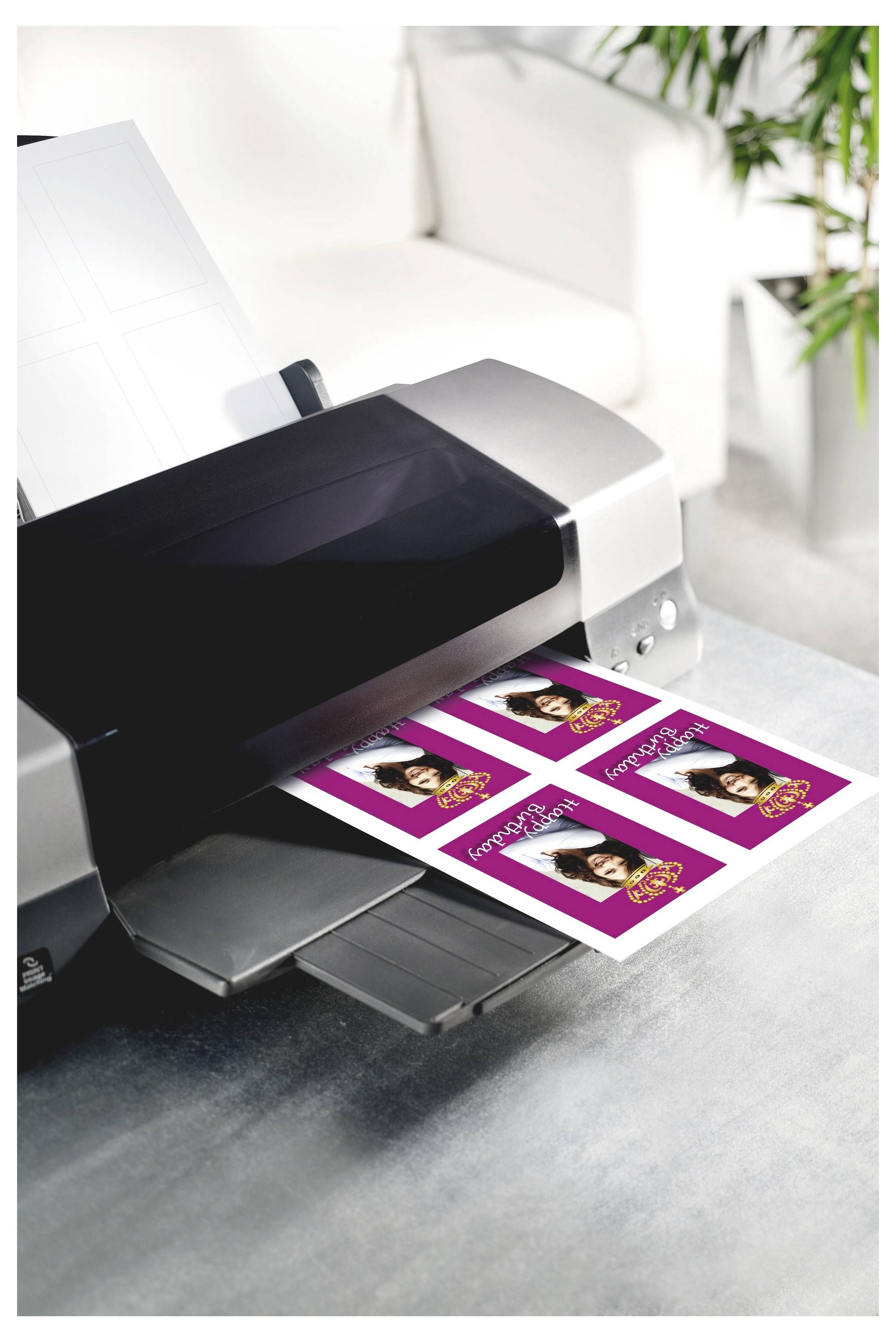 Tiskárna fotografií vytvářející čtyři purpurové pohlednice velikosti s portrétem ženy a textem na stole v jasném obývacím pokoji