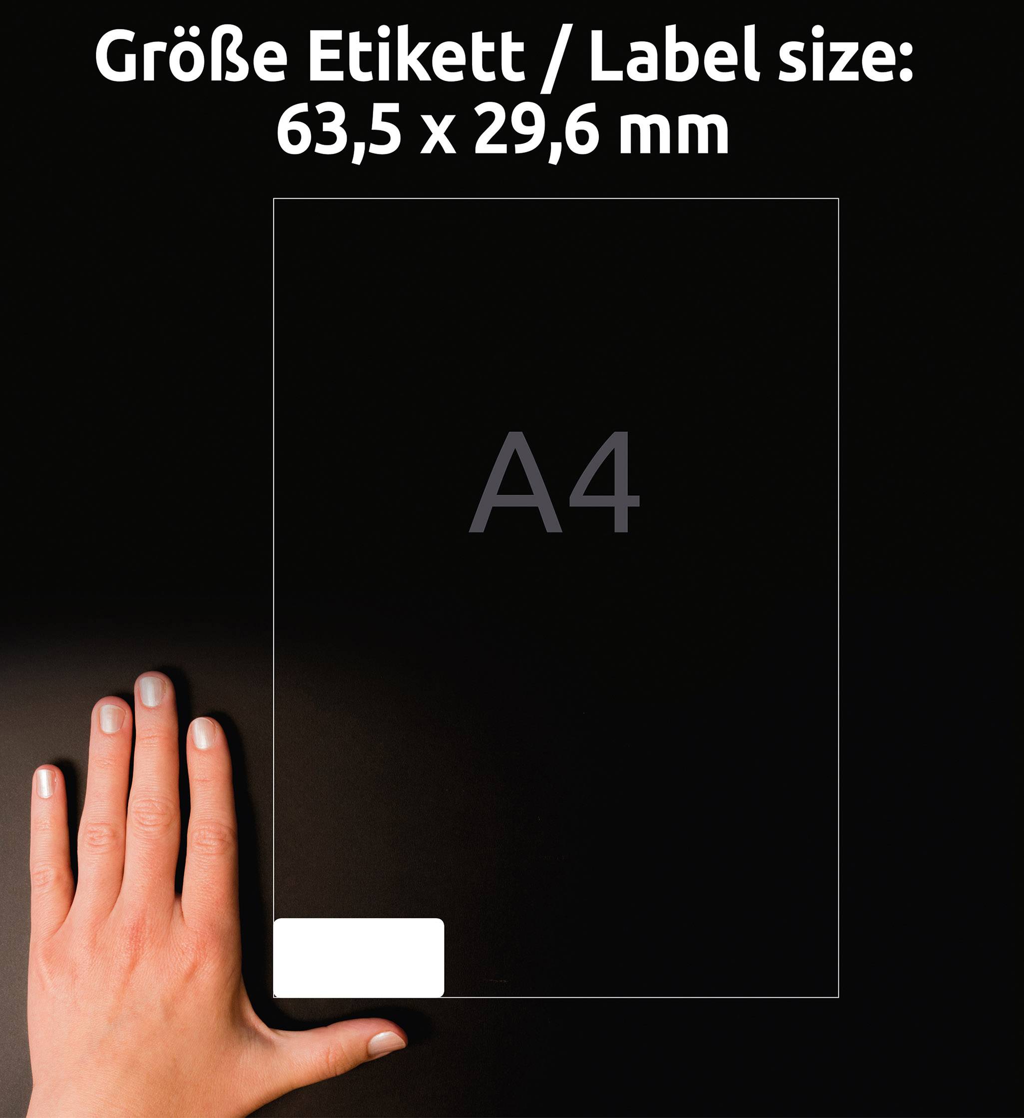 Štítek velikosti A4 s rozměry 63,5 x 29,6 mm. Na levé straně obrázku je ruka, která ukazuje na bílý štítek v dolním rohu.