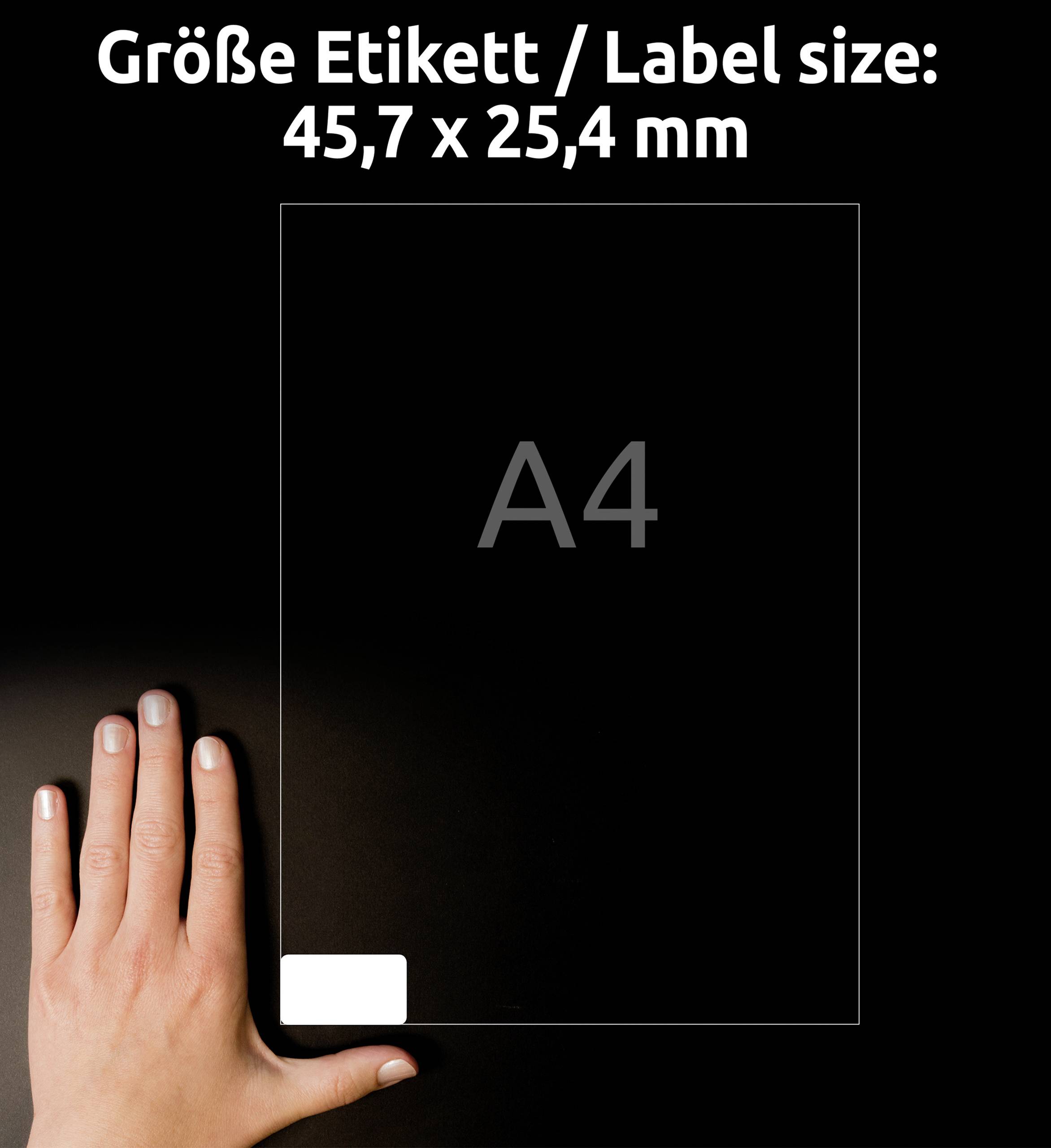 Ruka vedle průhledného papíru formátu A4 ukazuje velikost etikety 45,7 x 25,4 mm a slouží jako reference pro srovnání velikosti.
