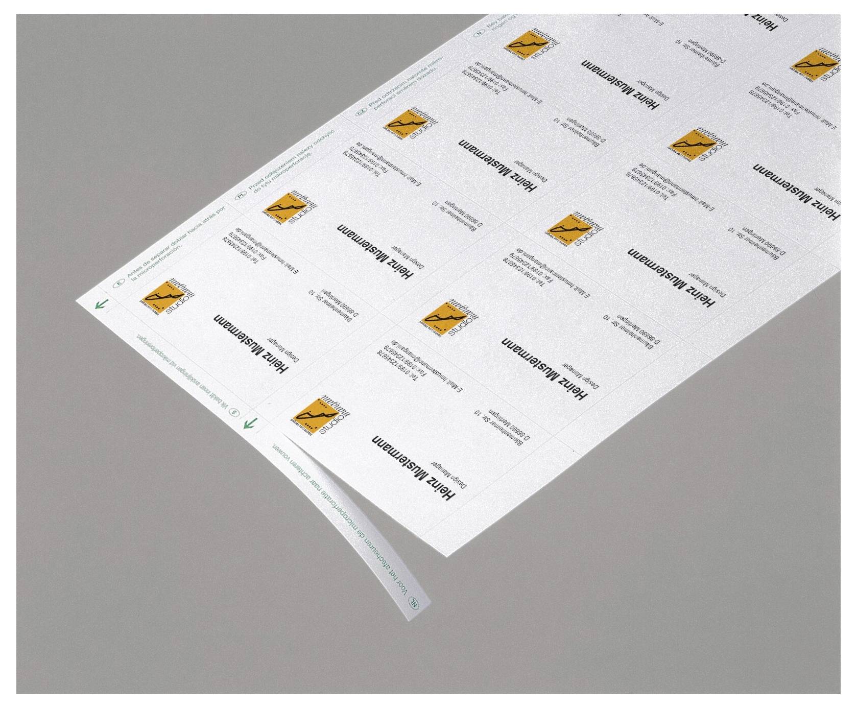 List tištěných přepravních štítků nebo samolepek s opakujícími se oranžovými ikony varování, zobrazené diagonálně na šedém pozadí.
