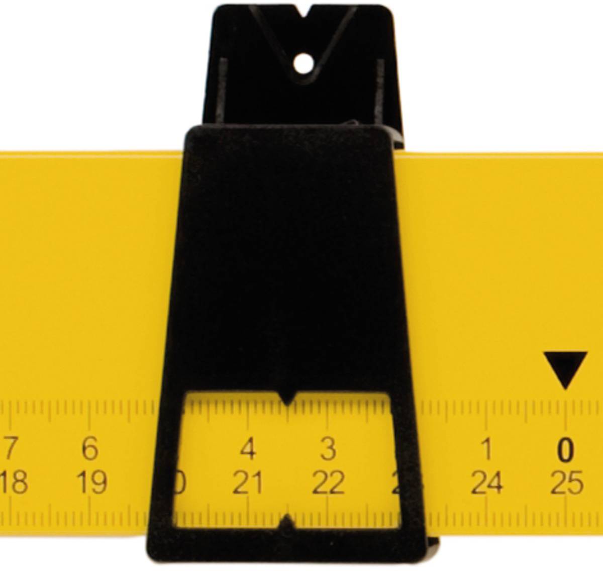 „Detailní záběr žluté pravítka, které je drženo velkou černou svorkou. Centimetrová stupnice viditelná od 16 do 25."