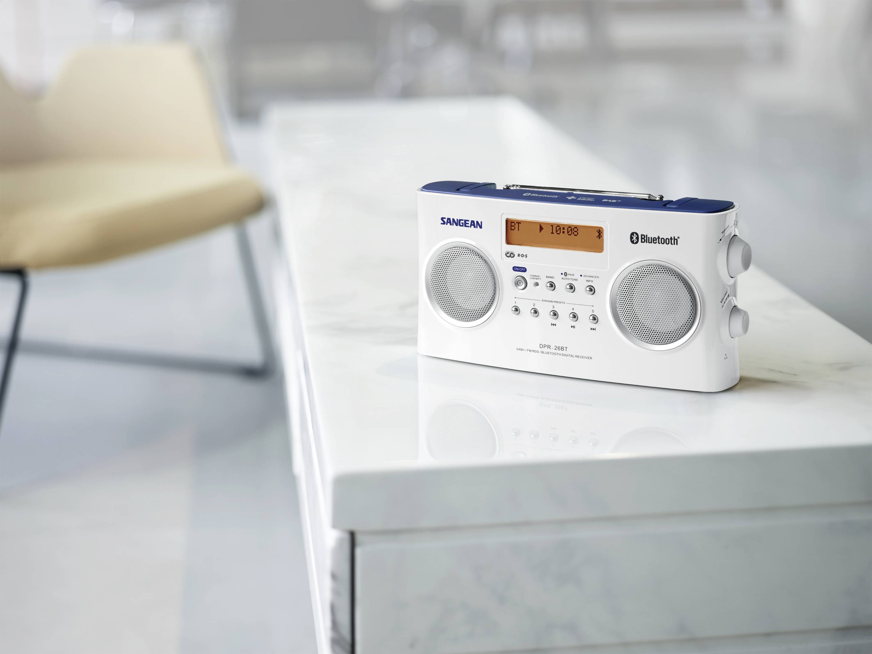 Přenosné rádio s funkcí Bluetooth stojí na světlém mramorovém stolku v moderně zařízené místnosti.