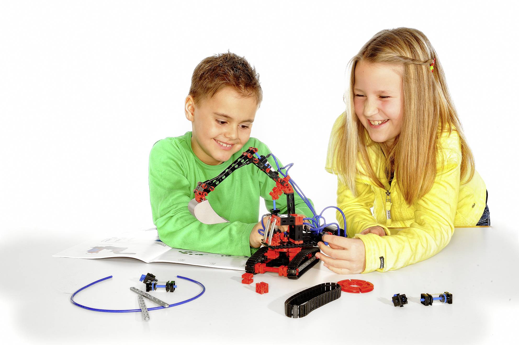 Děti si hrají se stavebnicí, montují mechanický model paže. Vypadají soustředěně a nadšeně.