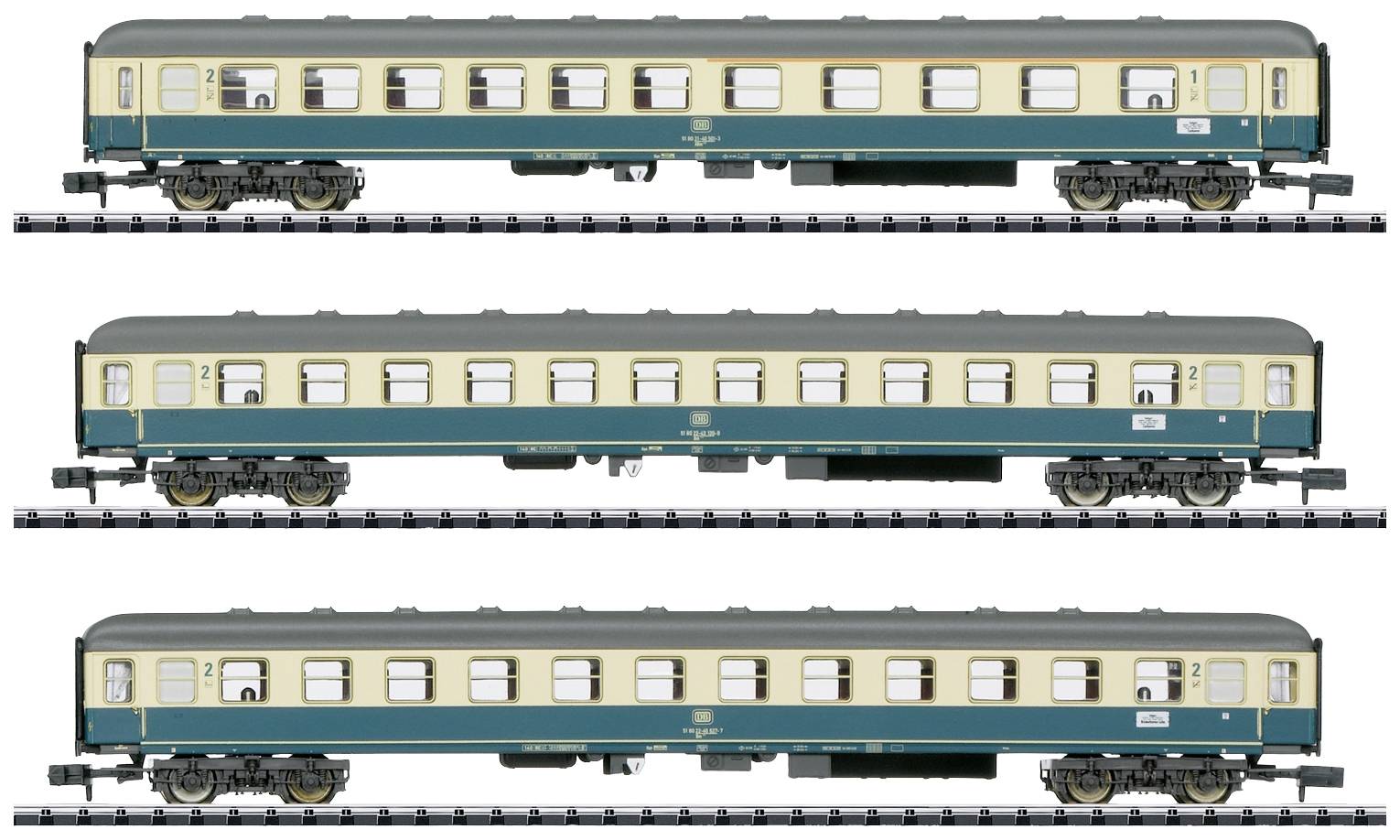 Tři osobní vagóny modelové železnice v zeleno-béžovém designu, uspořádané v horizontální řadě na kolejích.