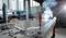 Kovová dílna s velkým pracovním stolem, svěrkami a jiskřícím svařovacím procesem v pozadí.