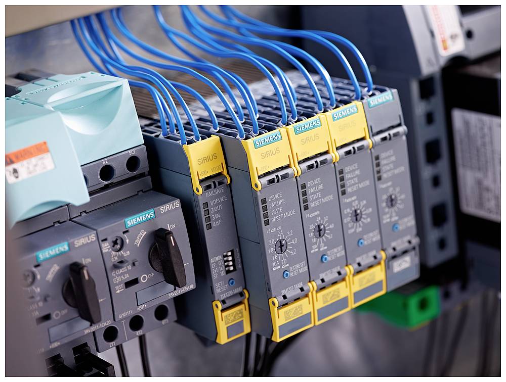 Rozváděč s několika zařízeními Siemens SIRIUS, propojenými modrými kabely. Zobrazuje elektronické řídicí komponenty.