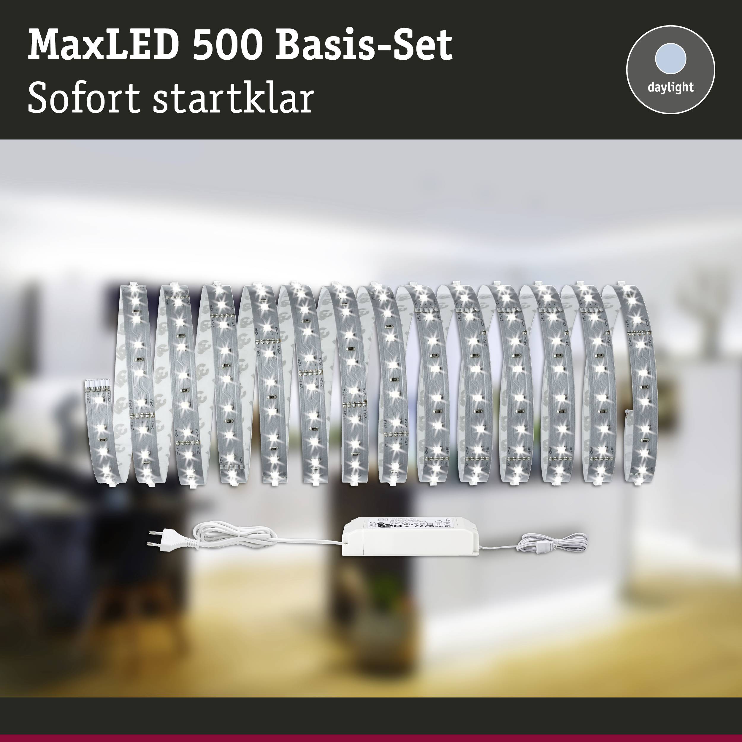 Základní sada LED pásku MaxLED 500 s řídicí jednotkou, okamžitě připravená k použití. V pozadí rozmazaný interiér.