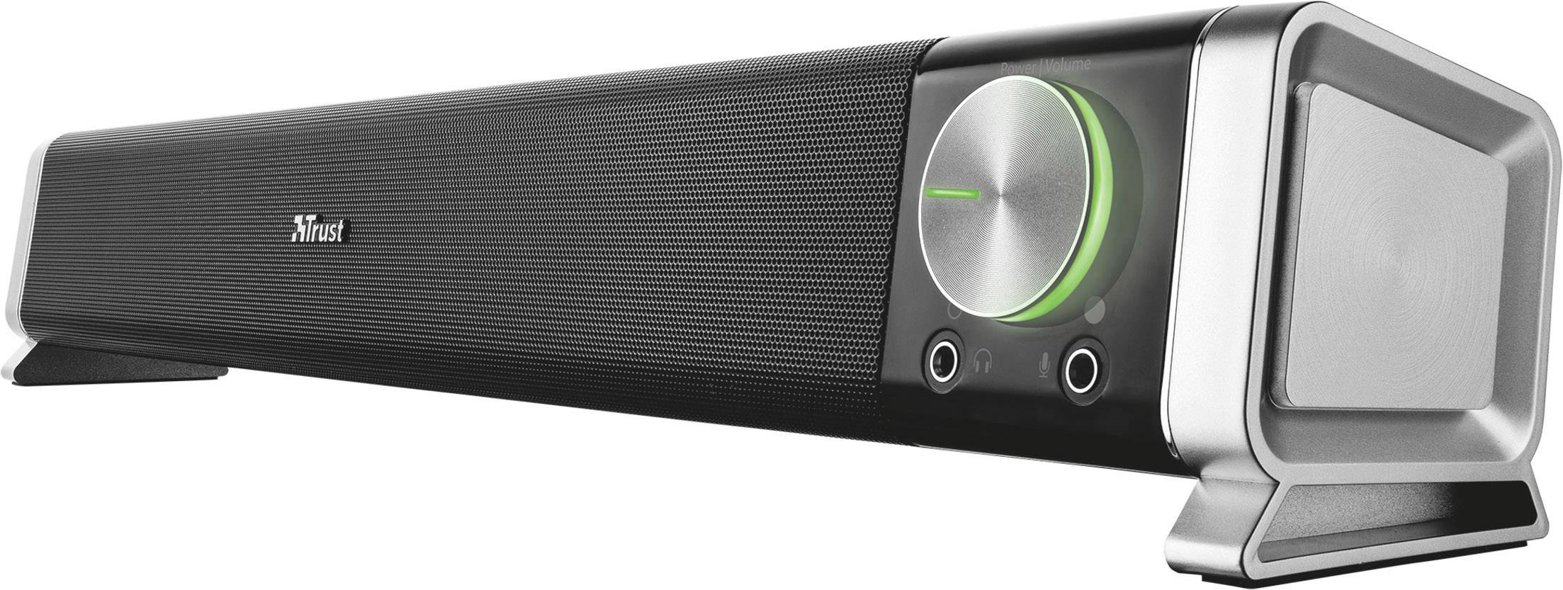 Černý soundbar se stříbrným ovladačem hlasitosti, zeleným světelným indikátorem, dvěma přípojkami a logem Trust vlevo.