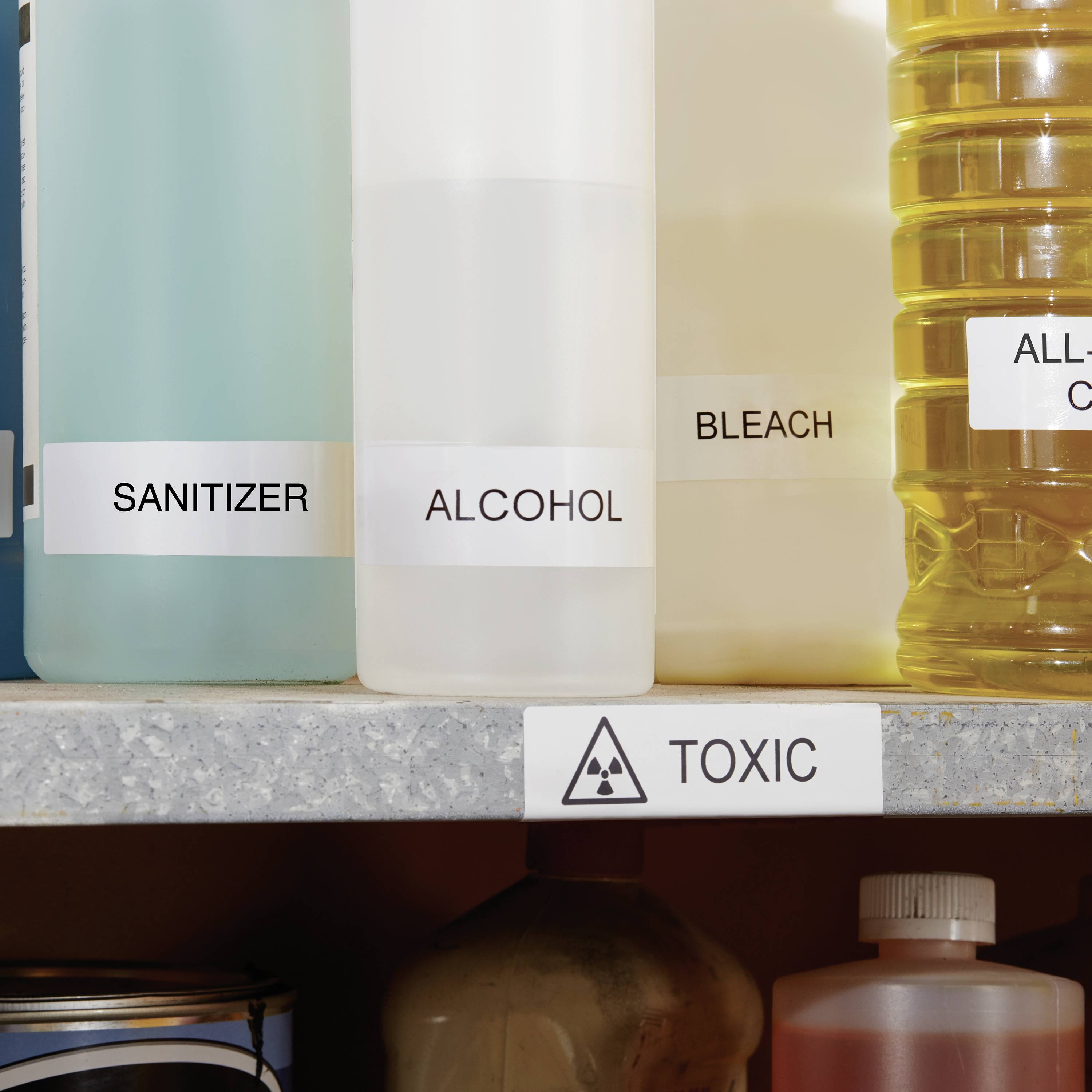 Police s lahvemi označenými 'Dezinfekce', 'Alkohol', 'Bělidlo'. Dole výstražná cedule s nápisem 'Toxické'.