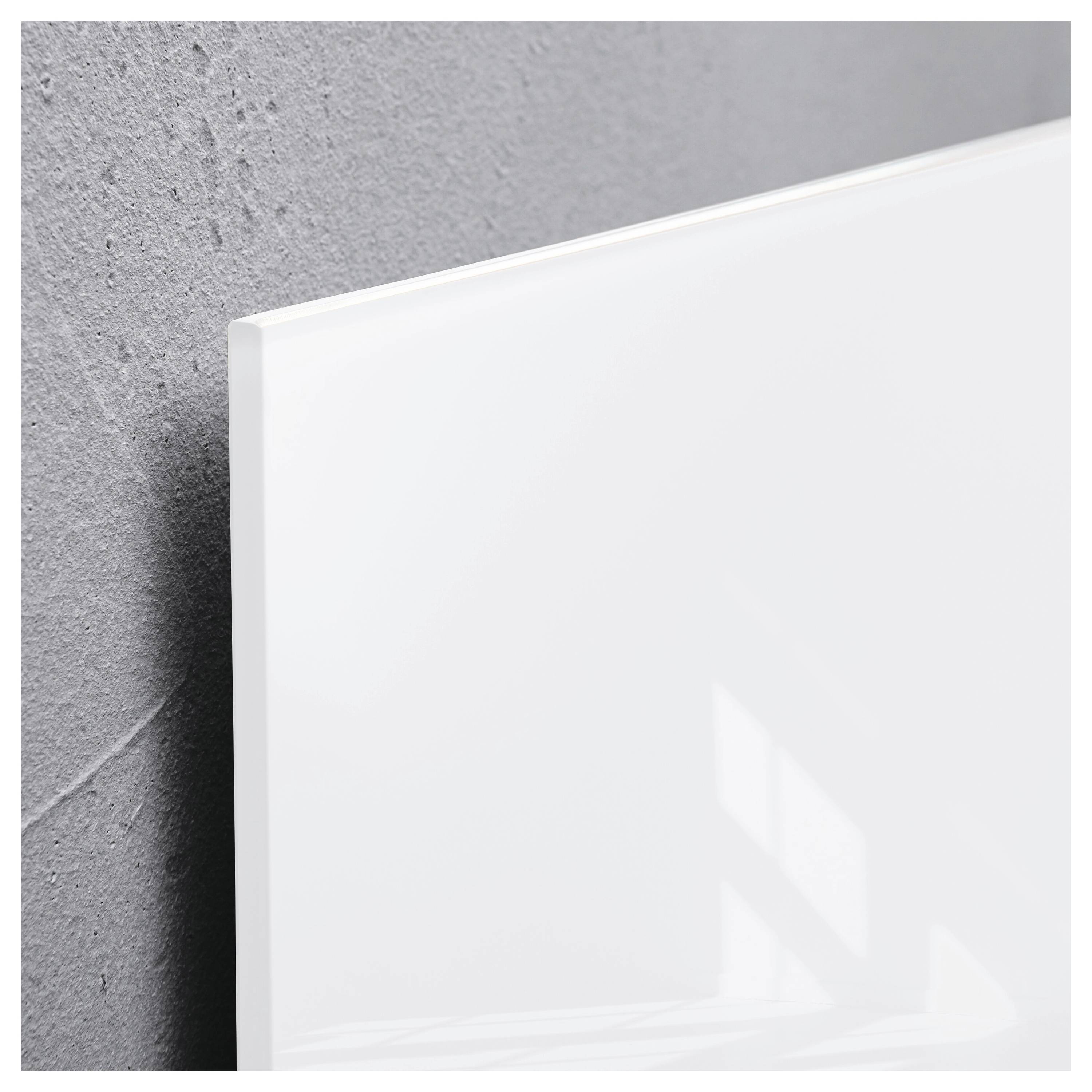 Detailní záběr na jednoduchou bílou plátnu nebo panel opřený o šedou strukturovanou stěnu, se měkkými odrazy světla.