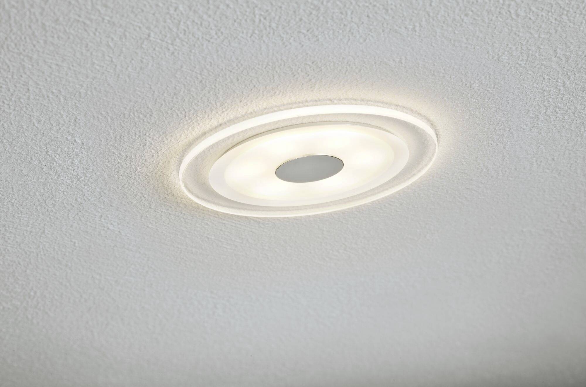 Kulatá stropní LED svítidlo uprostřed bílého strukturovaného stropu. Vyzařuje jemné bílé světlo.