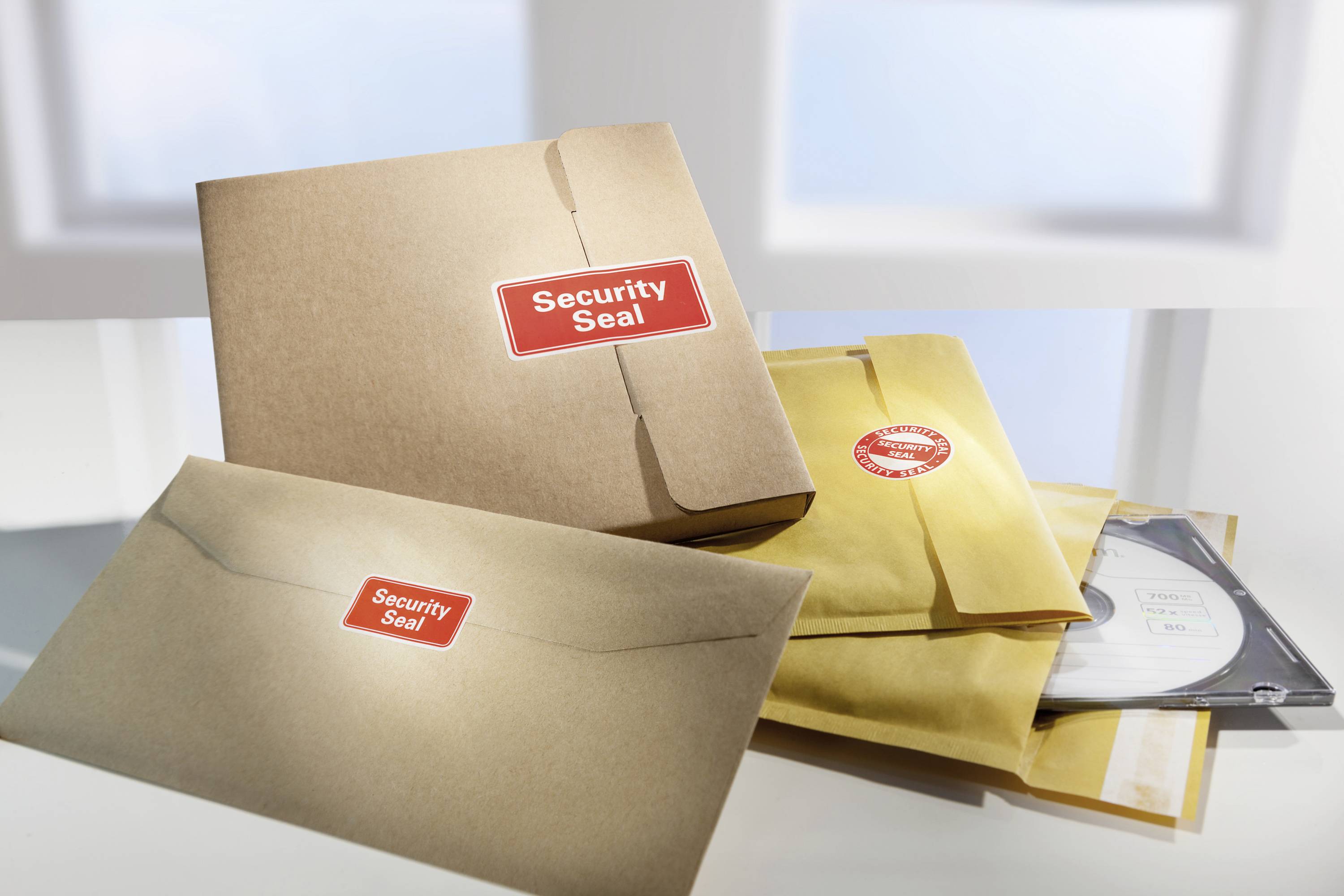 Obálky s červenými nálepkami 'Security Seal'. Některé obsahují CD a dokumenty. Symbolizují bezpečnost a ochranu informací.