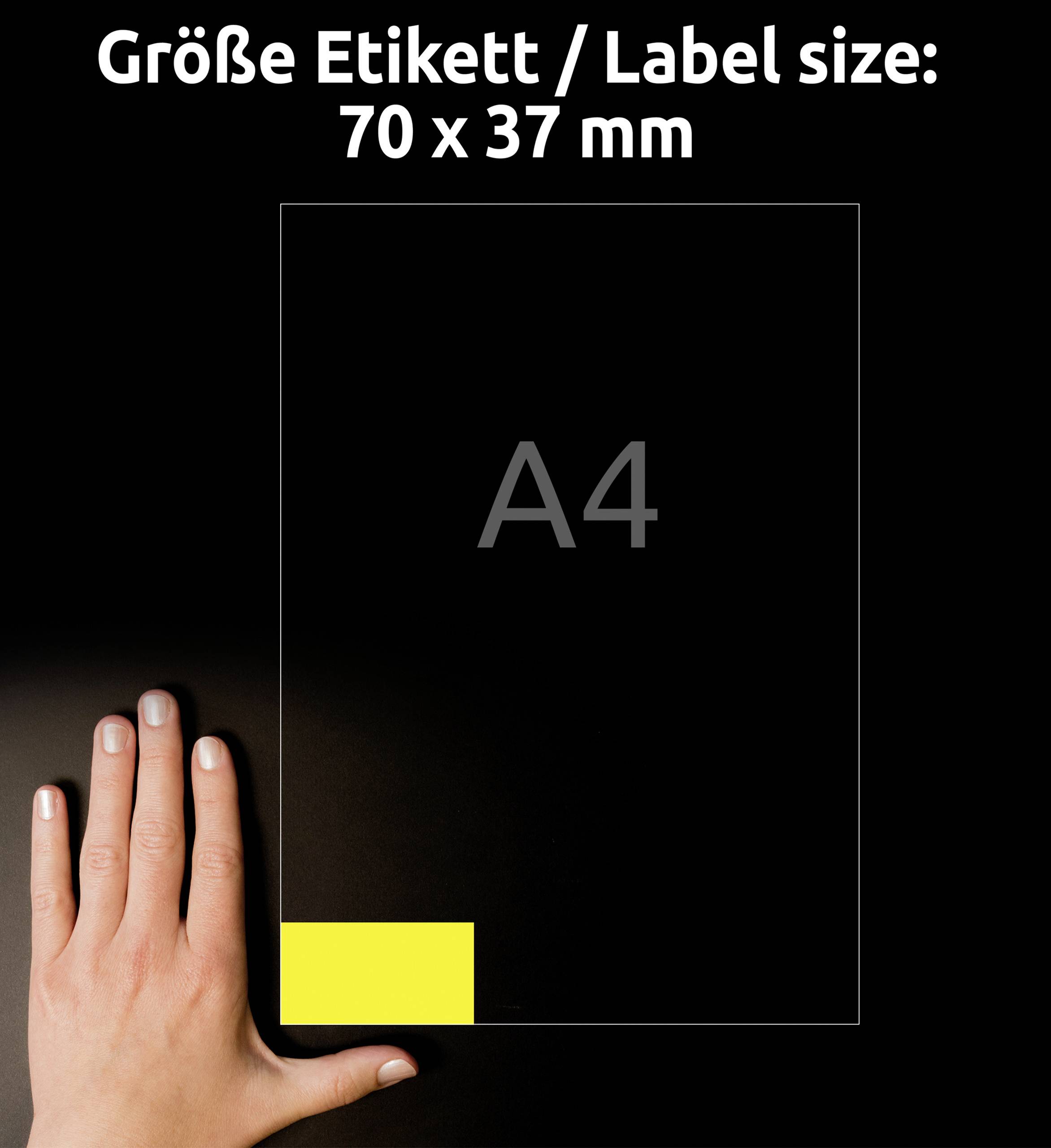Jedna ruka ukazuje na žlutou etiketu ve formátu 70 x 37 mm na listu formátu A4 na černém pozadí.