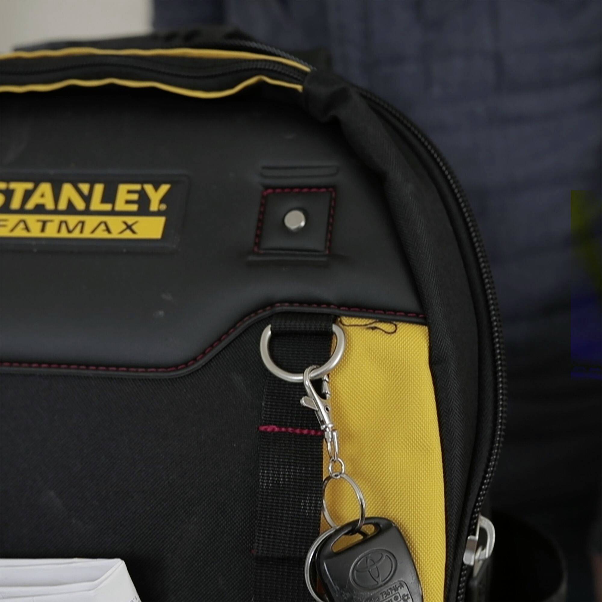 Batoh s nápisem 'Stanley Fatmax'. Na straně visí svazek klíčů s černým klíčem od auta.