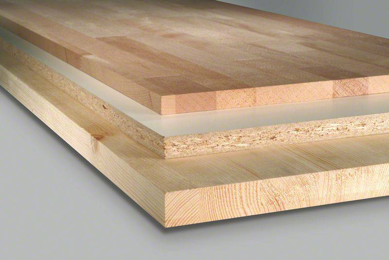 Tři různé dřevěné desky naskládané na sebe: nahoře tenké lamino, uprostřed dřevotříska, dole masivní silné dřevo.