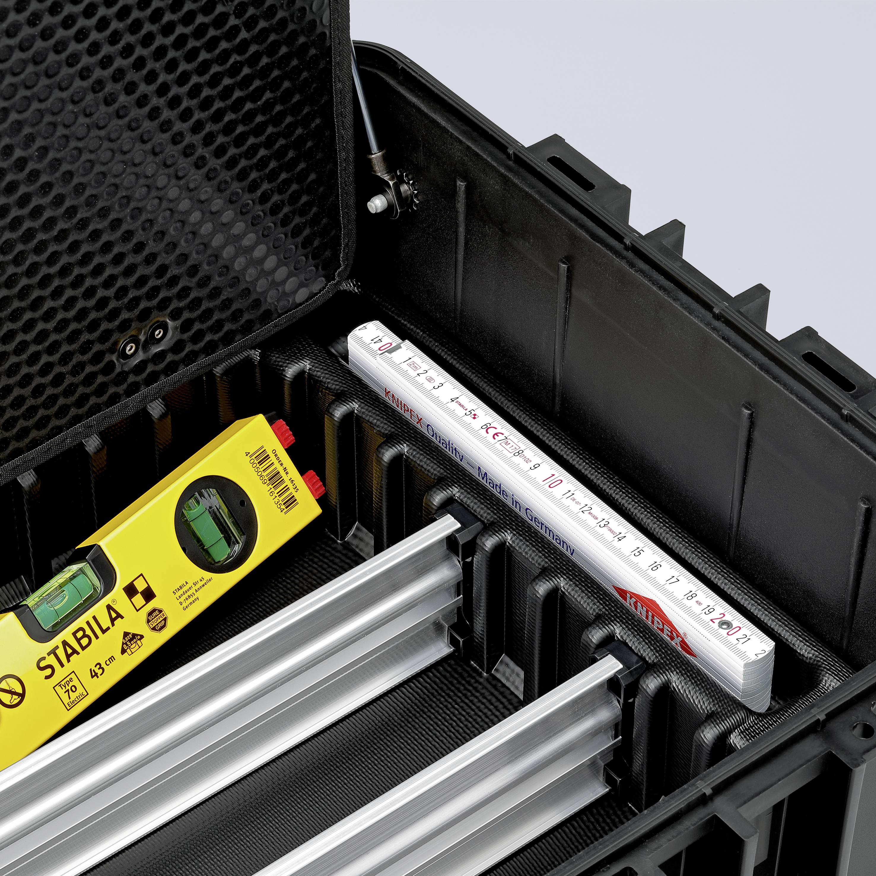 Otevřený černý kufřík na nářadí s měřicím a nivelačním přístrojem značky Stabila, hliníkovými přihrádkami na nářadí a bílou měřicí stupnicí.