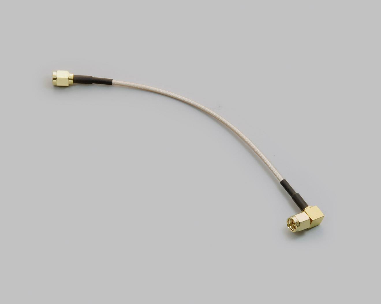Krátký kabel se zlatým konektorem na každém konci, který leží v mírném oblouku. Pozadí je jednoduše šedé.