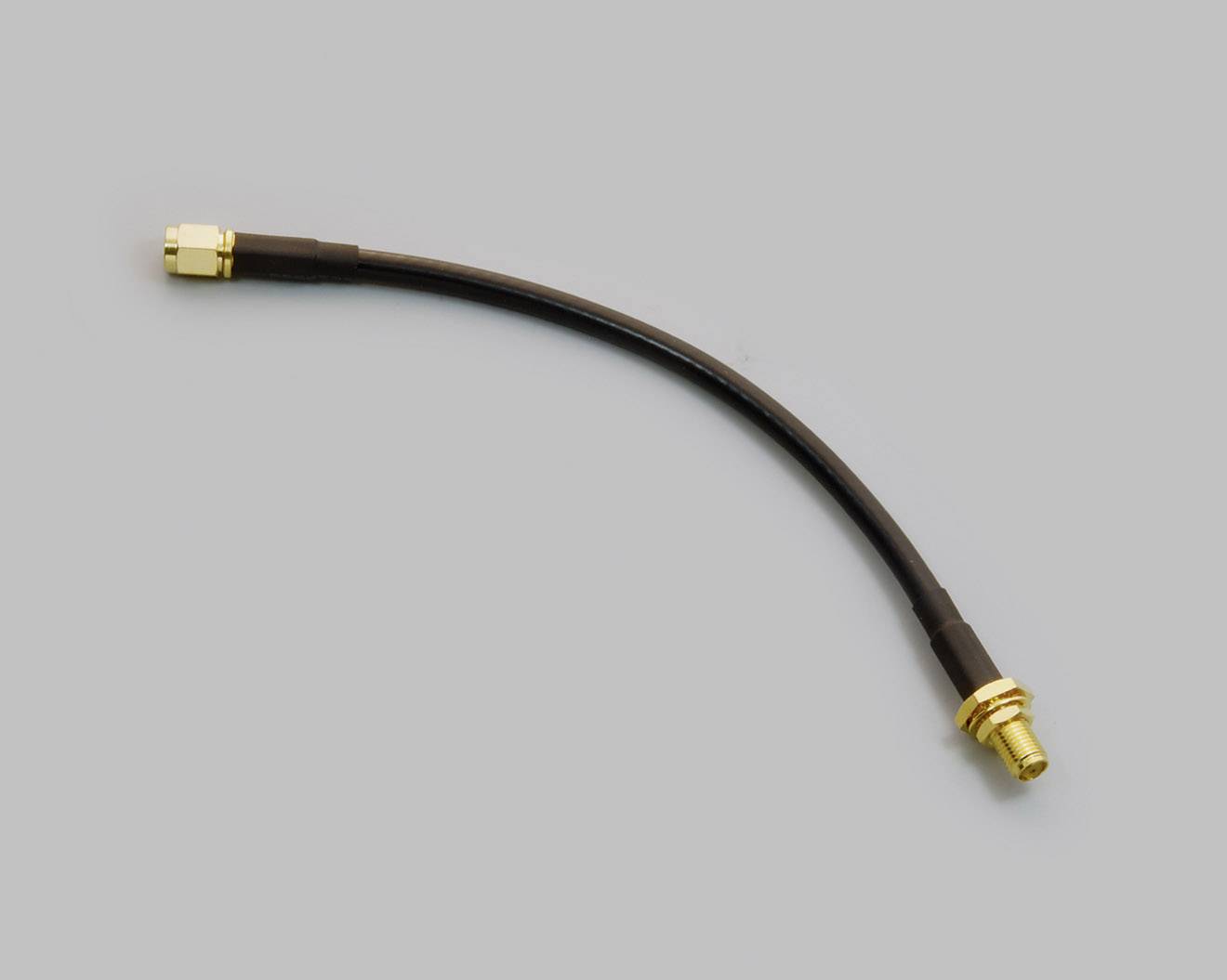 Koaxiální kabel se zlatými konektory na obou koncích na šedém pozadí.