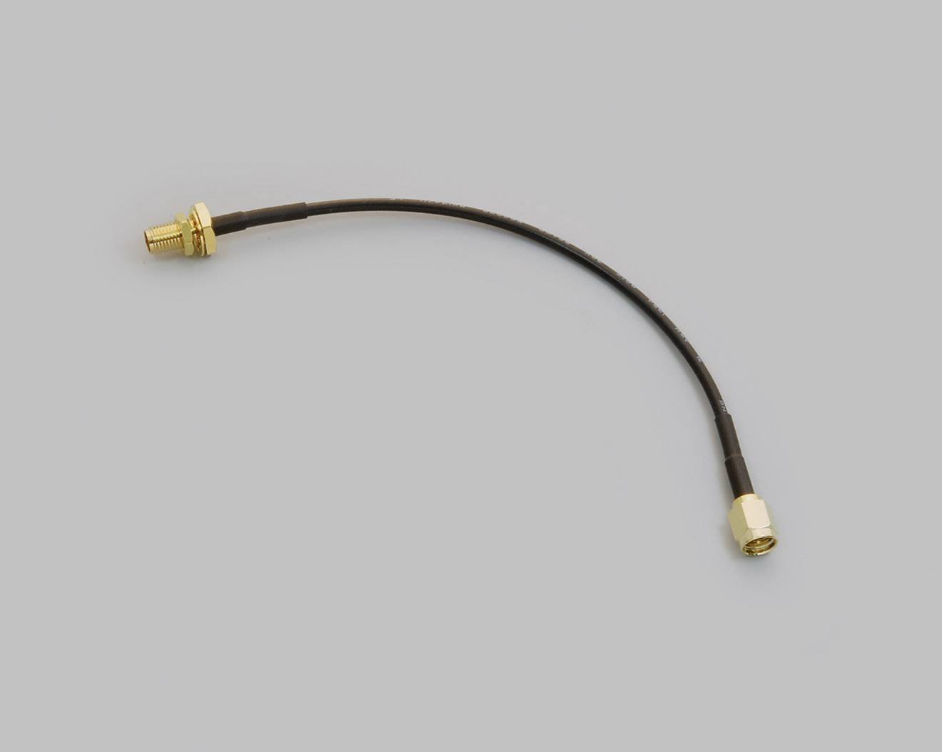 Kabel se dvěma zlatě zabarvenými konektory na koncích na šedém pozadí.