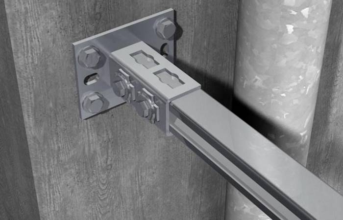 Montáž ocelového nosníku na betonové stěně pomocí velkých šroubů a matic, demonstrující stabilitu a konstrukční techniku.