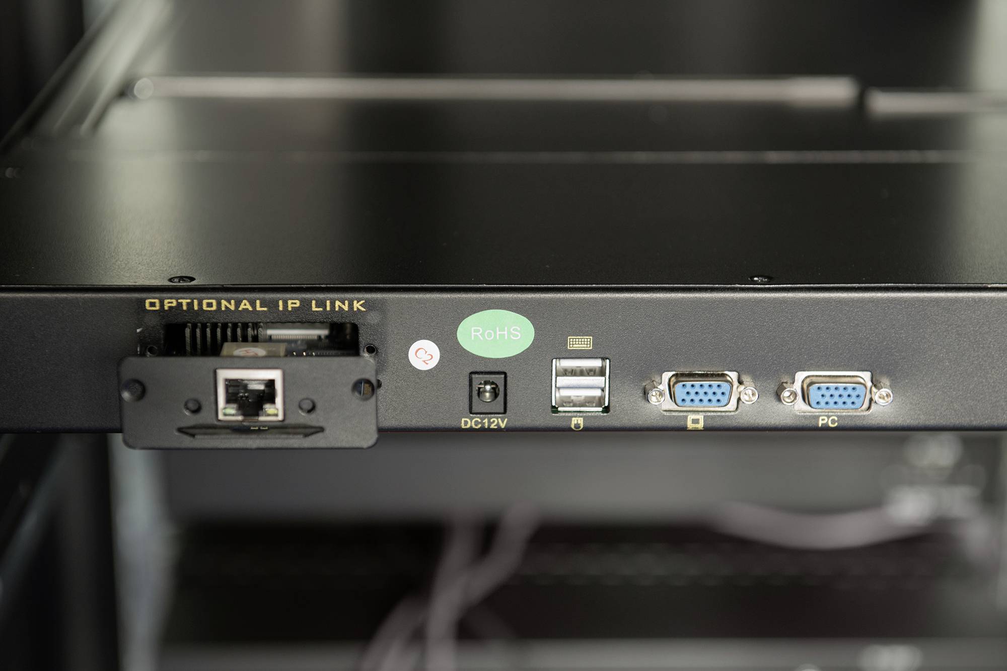 Zadní strana síťového zařízení s připojeními: Ethernet, USB, napájení DC12V, VGA pro připojení PC. Štítek RoHS je viditelný.
