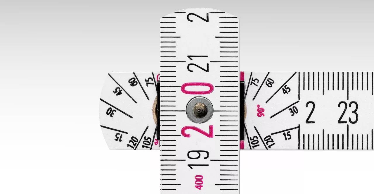 Metr v detailním záběru ukazuje čísla 19 až 23 v červených a černých značkách na světlém pozadí.