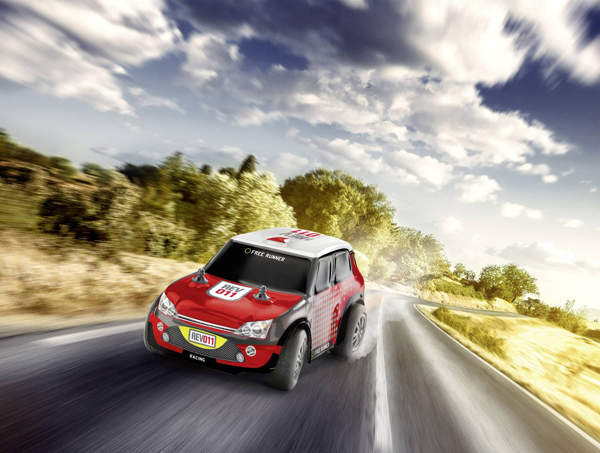 Červené rallyové auto dynamicky projíždí zatáčkami venkovské silnice v krajině obklopené stromy a pod zataženou oblohou.