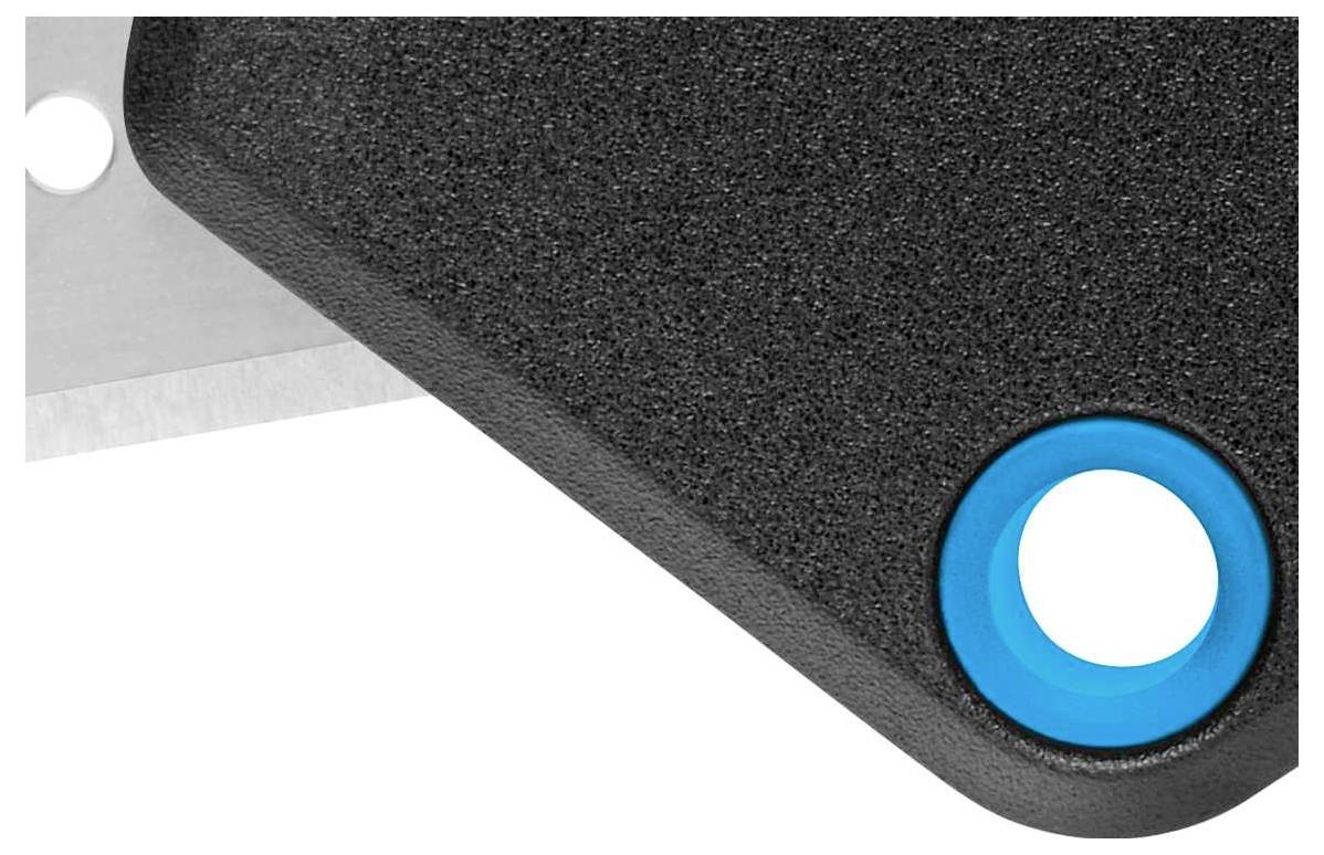 Roh kovového předmětu s černým povrchem, modré výztuhy otvoru a částečný pohled na nůž v pozadí.