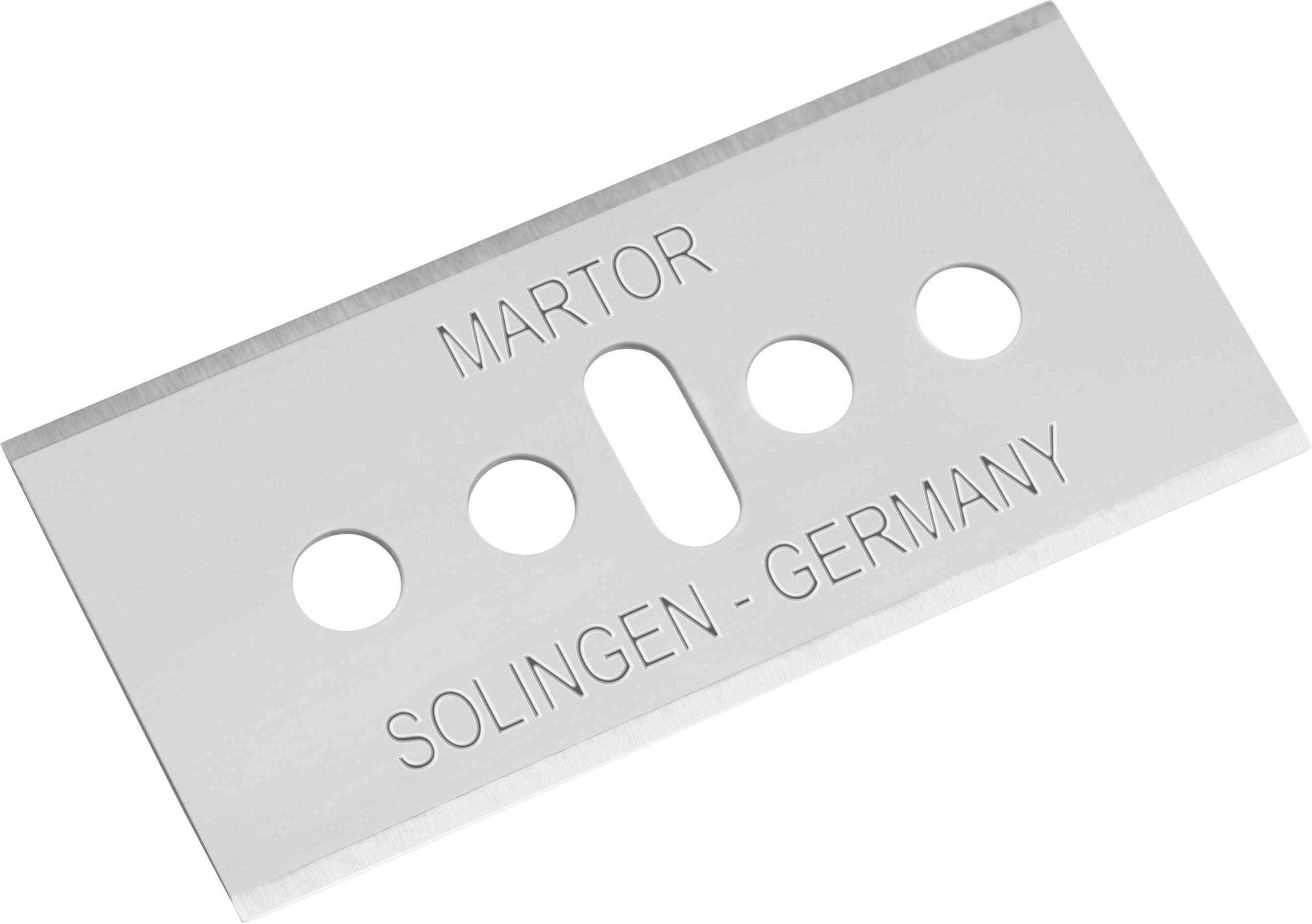 Plochá bezpečnostní čepel z kovu s nápisem 'Martor Solingen - Germany', která vykazuje čtyři kulaté otvory a jeden oválný štěrbinový otvor.