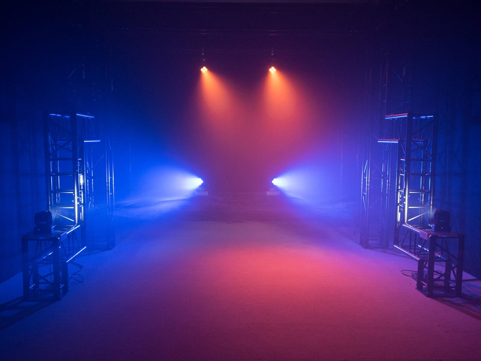 Prázdné jeviště s modrým a červeným světlem reflektorů, které vytváří atmosférickou náladu.